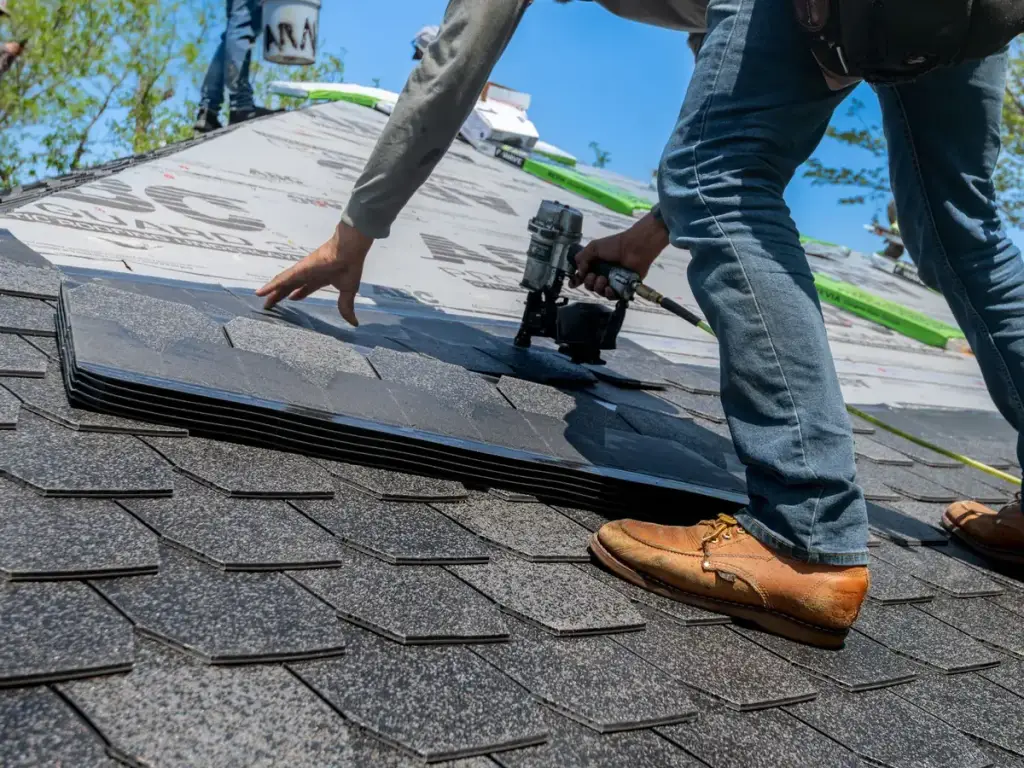Roofer fitting asphalt shingles on a residential roof