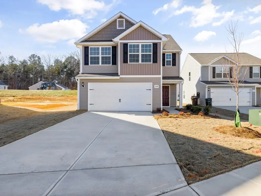 Wide concrete driveway leading to a two storey house