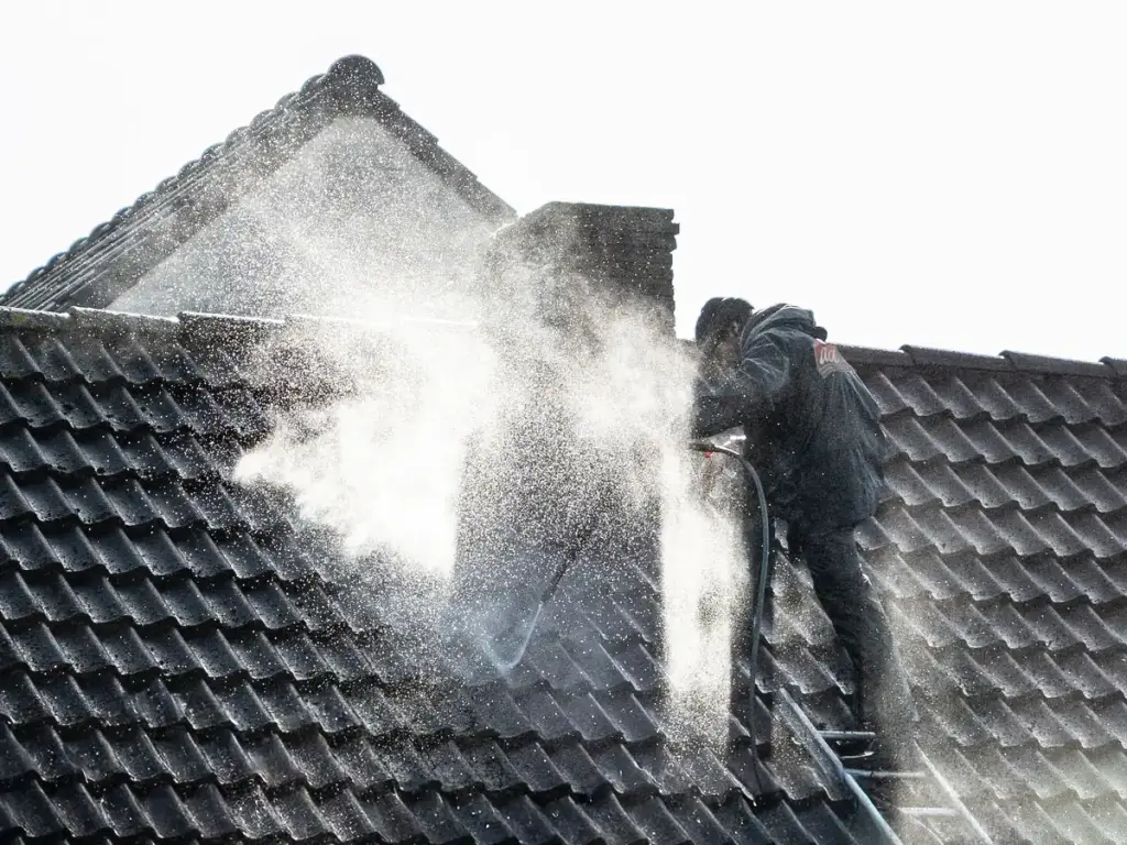 Worker pressure washing a tile roof